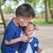 Child helping his sister with her mask