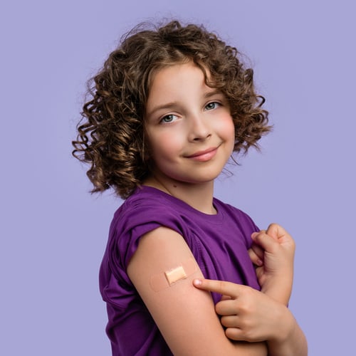 Vaccinated! Young girl shows the bandage from her flu vaccine